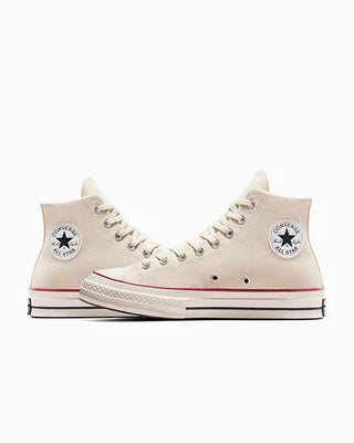 Beige high-top sneakers with white laces and red soles on a white background