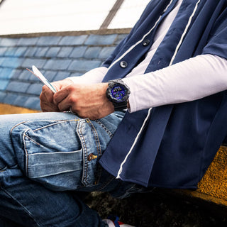Guy with a pink hat sporting the G-SHOCK GA-700VB-1A watch, featuring black and blue violet accents, exuding a trendy vibe