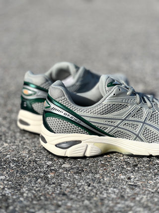 ASICS GT-2160 in Seal Grey/Jewel Green showcased on the concrete at Drift House Cocoa Beach parking lot.