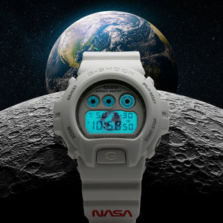 Image of the G-Shock DW6900NASA237 Digital Watch, a tribute to NASA. The watch is featured in front of the moon and earth in outer space.