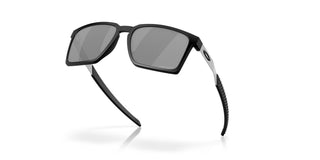 Oakley Exchange Sun Sunglasses in Satin Black with Prizm Black lenses, mixed material O Matter front with stainless steel temples and B1B grip textured Unobtainium earsocks, 11% light transmission grey base lens optimized for bright light, heritage-inspired design