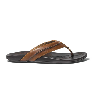 Olukai Mea Ola leather sandals in Tan and Dark Java with whipstitched straps and laser-etched footbed artwork.