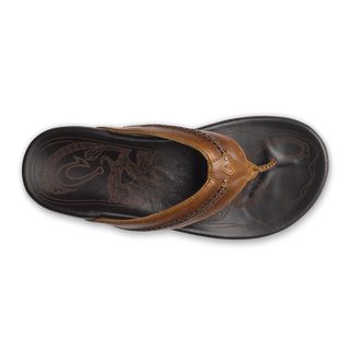 Olukai Mea Ola leather sandals in Tan and Dark Java with whipstitched straps and laser-etched footbed artwork.