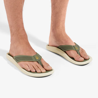 Side view of an OluKai Ulele sandal in Shadow Green with laser-cut straps, mustard-colored lining, and a textured cream sole.