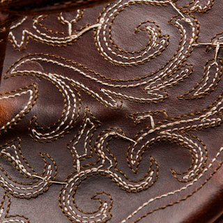 Side view of an OluKai Mekila sandal in Natural/Natural with brown leather straps, stitched edges, and decorative artwork across the footbed.