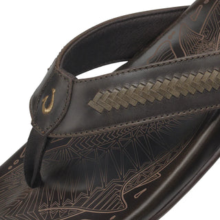 OluKai Mea Ola Mano leather sandals in Dark Java/Mustang with woven straps and shark-inspired etched detailing.