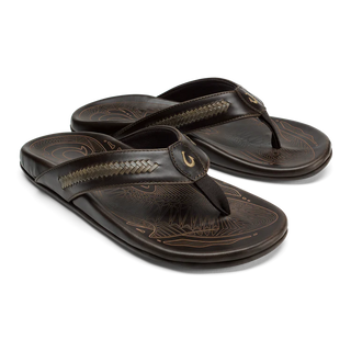 OluKai Mea Ola Mano leather sandals in Dark Java/Mustang with woven straps and shark-inspired etched detailing.