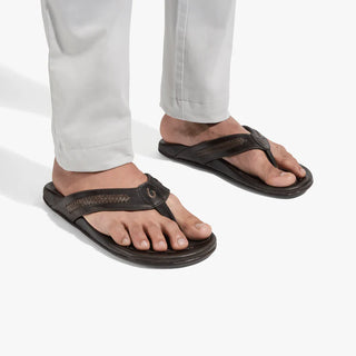 OluKai Mea Ola Mano leather sandals in Dark Java/Mustang with woven straps and shark-inspired etched detailing.