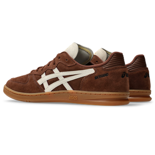ASICS SKYHAND OG in reddish brown and oatmeal with suede panels, gum outsole, and retro handball-inspired silhouette.