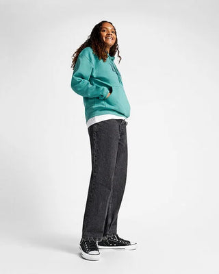 Person wearing a teal hoodie, white shirt, black jeans, and black sneakers on a white background