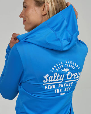 Bold blue Salty Crew hooded sunshirt with long sleeves, printed chest and back graphics, and lightweight stretch performance fabric.