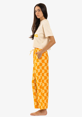A woman wearing Duvin's Golden Hour Pants with relaxed fitting cabana style, made from a blend of 58% rayon and 42% polyester, featuring a wide-leg cropped style, adjustable drawstring, single back pocket, and a side hem woven label.