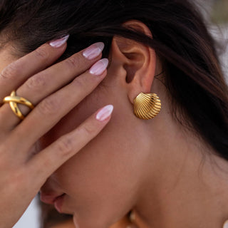 Gold earrings with minimalist sculptural design and smooth polished surface, secured with push back closure.