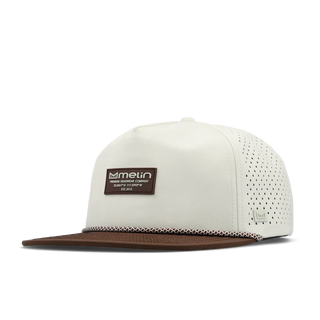 melin Coronado Brick Hydro Hat in Frosted Birch with an off-white crown, brown flat visor, rectangular melin patch, patterned rope trim, and perforated side panels.