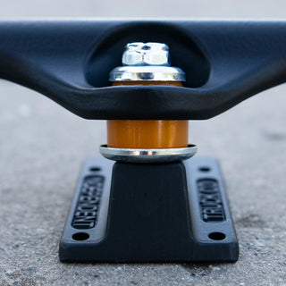 Independent 149 Stage 11 Blackout trucks with flat black powder coat, orange cushions, aluminum hanger, and chromoly axle.