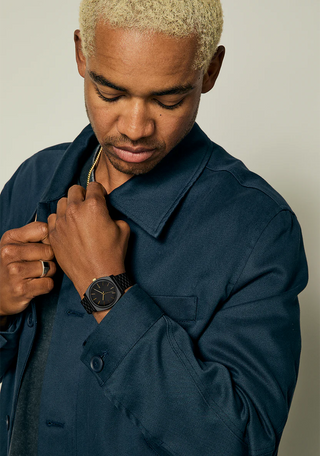 Nixon Time Teller Matte Black/Gold analog watch with black stainless steel bracelet and gold-tone dial accents.