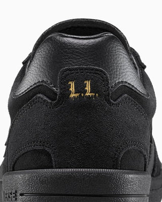 Black sneaker with gold logo on a white background