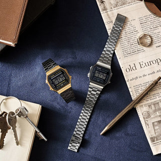 Two Casio watches on a blue surface with keys and a pen.