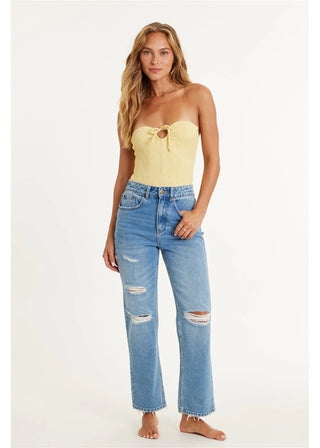 Woman wearing a yellow strapless top and blue jeans on a white background