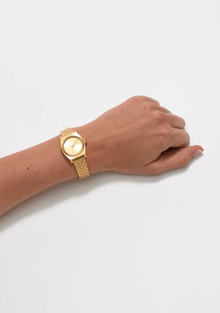 An image of the Nixon Small Time Teller All Gold watch, highlighting its golden design and stainless steel bracelet.