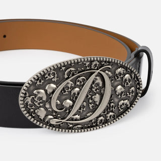 Dime Skull Leather Belt in Black with an oval silver-tone buckle featuring skull motifs and a large cursive D, a black keeper, and tan interior