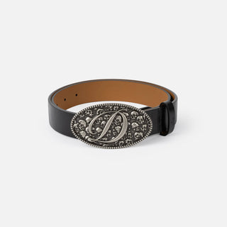 Dime Skull Leather Belt in Black with an oval silver-tone buckle featuring skull motifs and a large cursive D, a black keeper, and tan interior