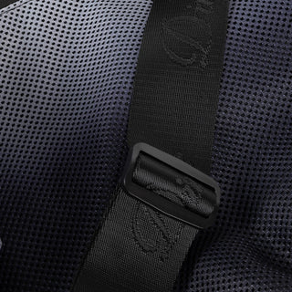 Close-up of a black backpack strap with a brand logo on a textured black background