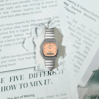 Casio Vintage AQ240E-4A watch with silver bracelet, pale matte orange dial, and analog-digital display.