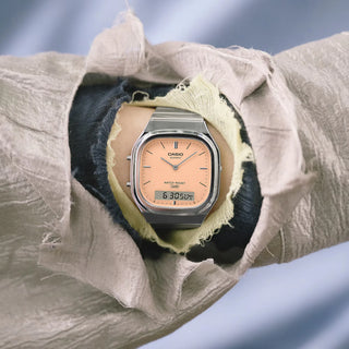 Casio Vintage AQ240E-4A watch with silver bracelet, pale matte orange dial, and analog-digital display.