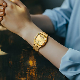 Gold wristwatch on a person's wrist with a blurred background