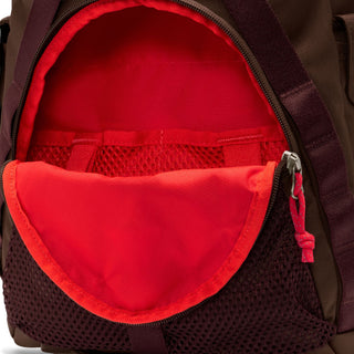 Close-up of the brown Nike ACG DAYMAX Backpack showing mesh paneling, adjustable webbing straps, buckle closures, and a red zipper pull