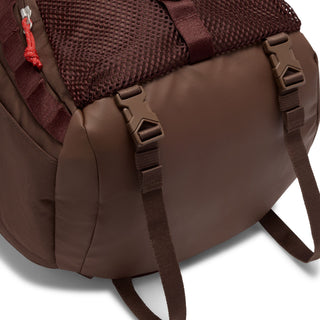 Close-up of the brown Nike ACG DAYMAX Backpack showing mesh paneling, adjustable webbing straps, buckle closures, and a red zipper pull