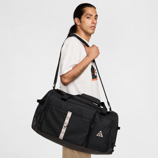 Nike ACG DAYMAX Duffel Bag in Black/College Grey with black carry handles, grey webbing straps, a front zippered pocket, and a small ACG logo