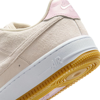 Close-up of a beige sneaker with a white sole and pink accents on a white background