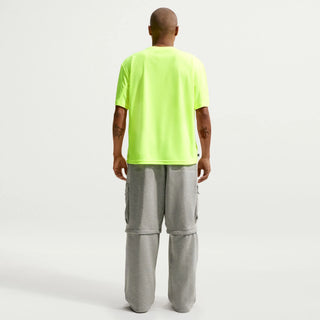 Person wearing a bright green t-shirt and gray pants on a white background
