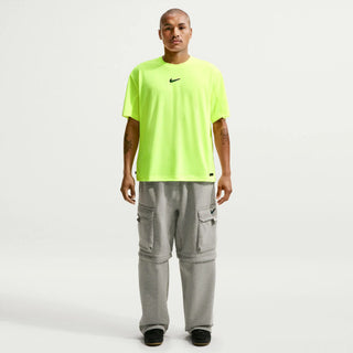 Person wearing a bright green Nike t-shirt and gray cargo pants on a white background