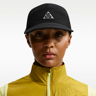 black Nike ACG Fly Unstructured Cap with a white embroidered ACG logo, holding the front of the bill.