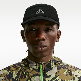 black Nike ACG Fly Unstructured Cap with a white embroidered ACG logo, holding the front of the bill.
