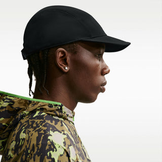 black Nike ACG Fly Unstructured Cap with a white embroidered ACG logo, holding the front of the bill.