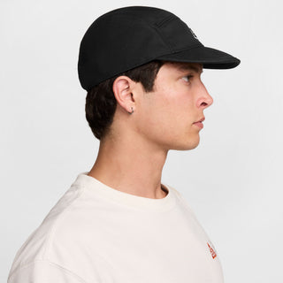 black Nike ACG Fly Unstructured Cap with a white embroidered ACG logo, holding the front of the bill.