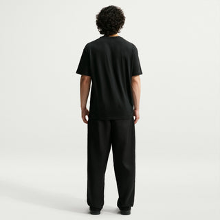 Rear view of a model wearing black Nike SB Men’s Skate Pants with a roomy, straight-leg silhouette