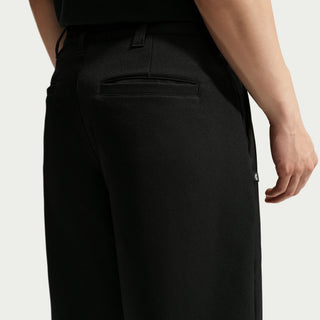 Rear view of a model wearing black Nike SB Men’s Skate Pants with a roomy, straight-leg silhouette