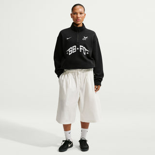 Person wearing a black hoodie with white text and graphics, white pants, and black shoes on a light gray background
