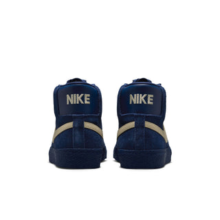A pair of navy blue high-top sneakers shown from the back, featuring a textured navy suede upper, beige stripes on the sides, and a beige 'NIKE' logo on the heel tabs.