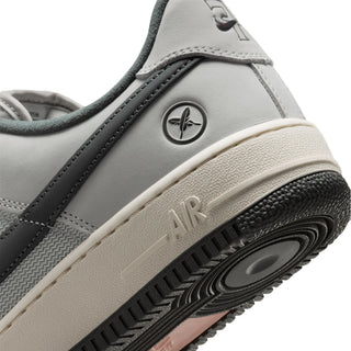 Close-up of the heel and midsole of a gray and black sneaker with a cream-colored midsole and a circular logo on the side.