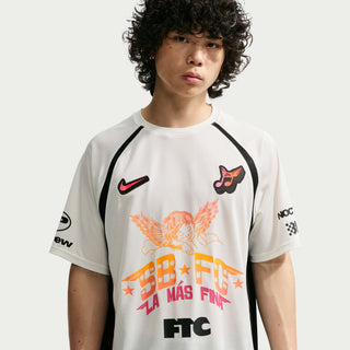 Person wearing a white sports jersey with various logos and text on a light gray background