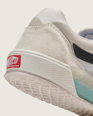 Close-up of a beige sneaker with a red label on a white background