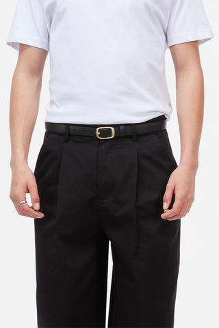 Person wearing a white t-shirt and black pants with a belt on a plain background