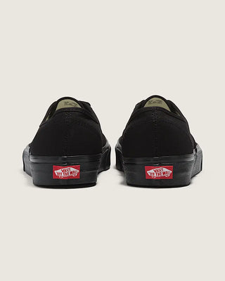 Black Vans shoes with red and white logo on a light gray background