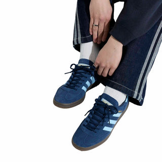 Person wearing blue sneakers with white stripes on a white background